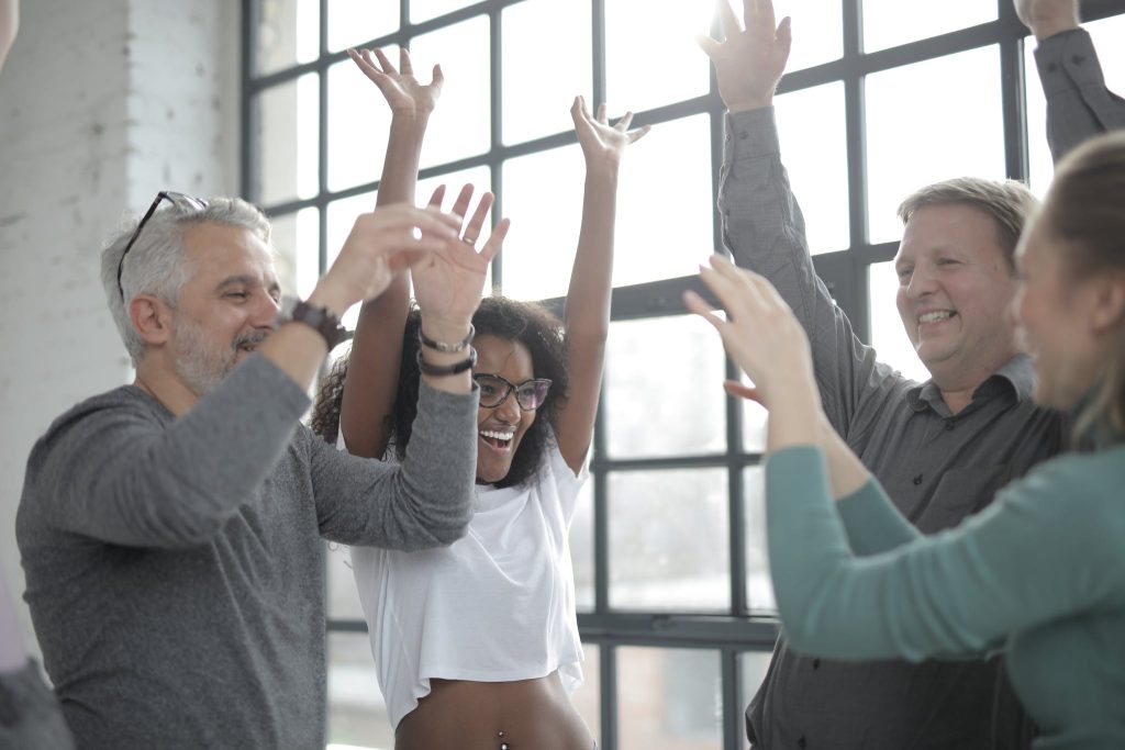 Group of happy multiracial friends raising hands and smiling